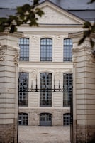 Un edificio histórico con fachada simétrica, ventanas grandes y una entrada central con reja de hierro forjado.
