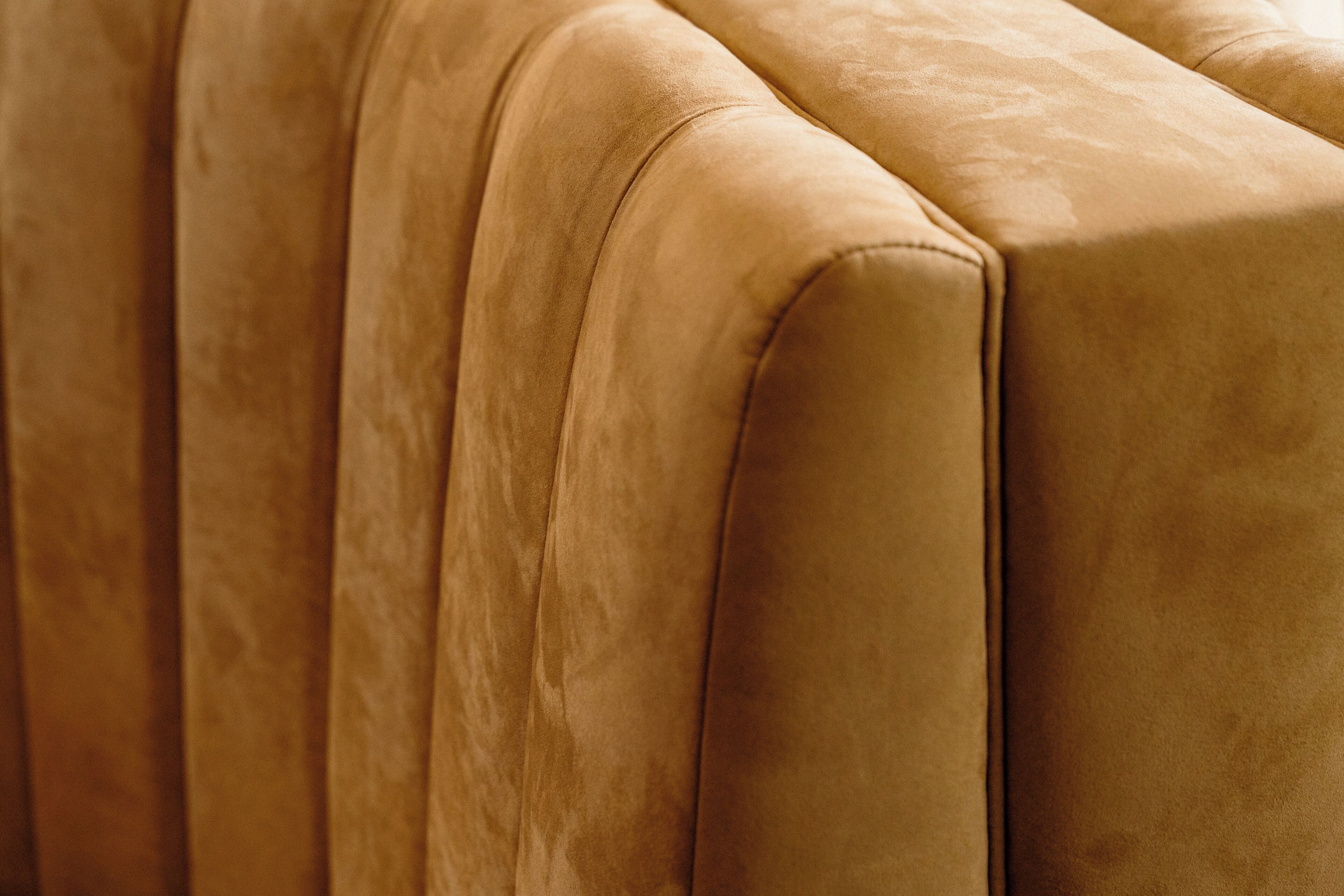 A close-up of a sofa with a smooth, padded surface and a curved backrest.
