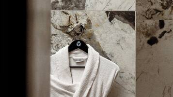 A bathroom with a marble floor, a towel hanging on a rack, and a pair of white slippers.