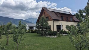 A two-story house with a sloped roof, solar panels, and a well-maintained lawn. - Eco clay & straw villa with mountain scenery (Žiar)