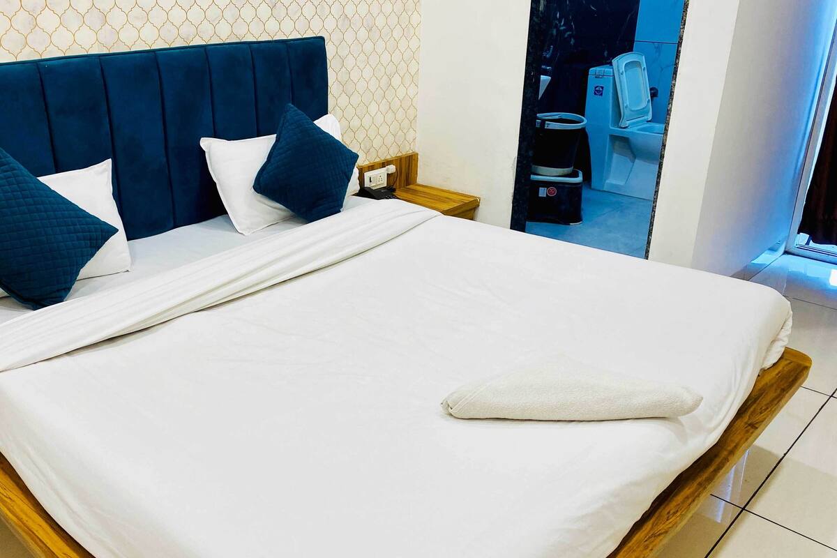 A neatly made bed with a blue upholstered headboard, white bedding, and two blue pillows.