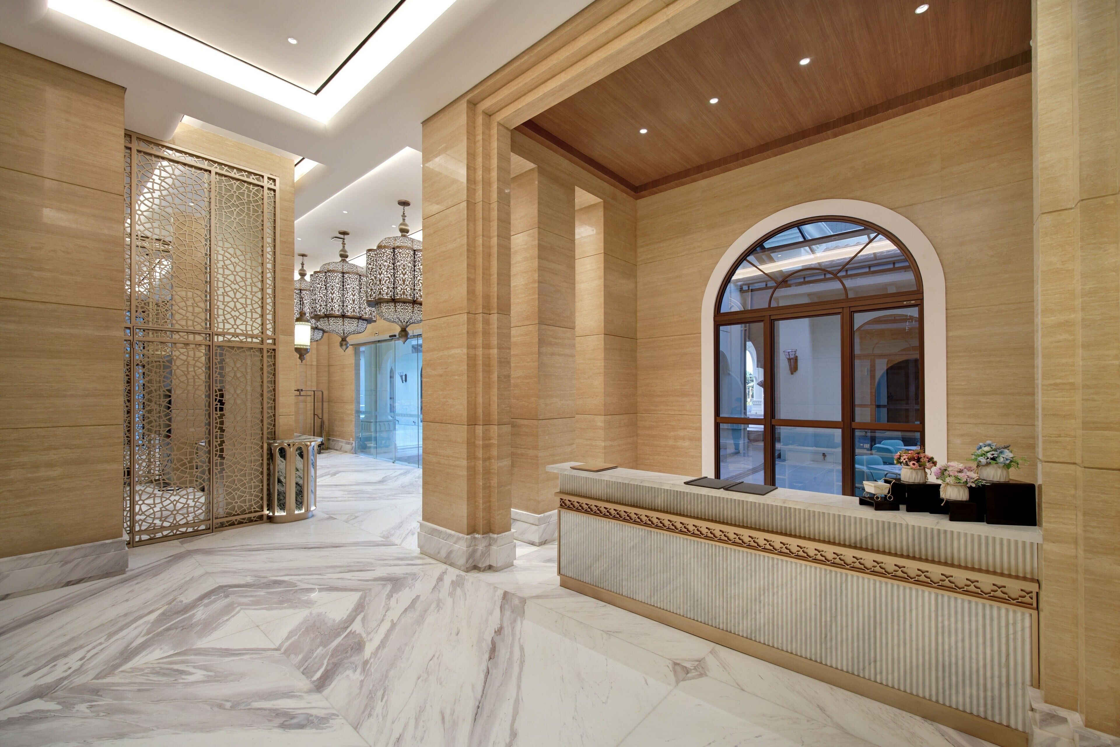 A spacious lobby with marble flooring, a reception desk, and a decorative screen.