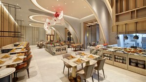 A modern restaurant with a long counter, multiple dining tables, and a central bar area.
