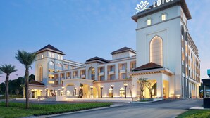 A multi-story hotel with a prominent Lotus symbol on the facade, featuring arched windows and a symmetrical design.