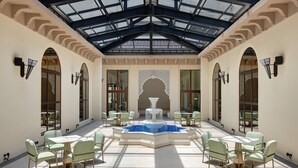 A spacious indoor courtyard with a central fountain, surrounded by seating areas and large windows.
