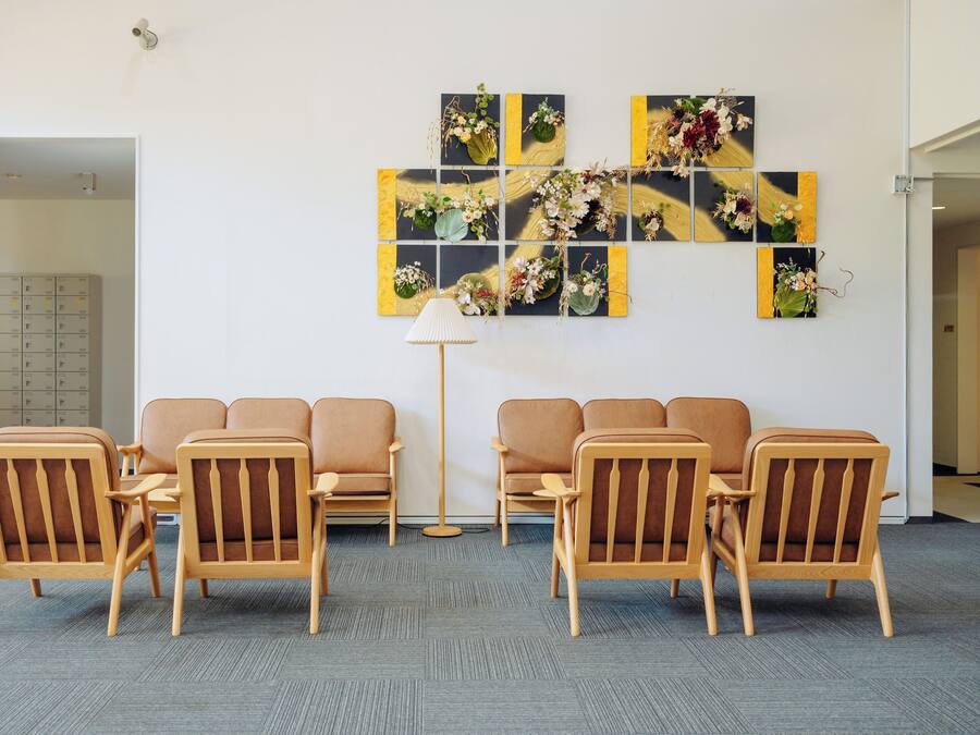 A waiting area with six wooden chairs and a floor lamp.