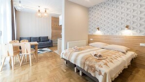 A modern bedroom with a wooden bed, a dining area with a table and chairs, and a patterned wall. - AMI ZAKOPANE (Zakopane)