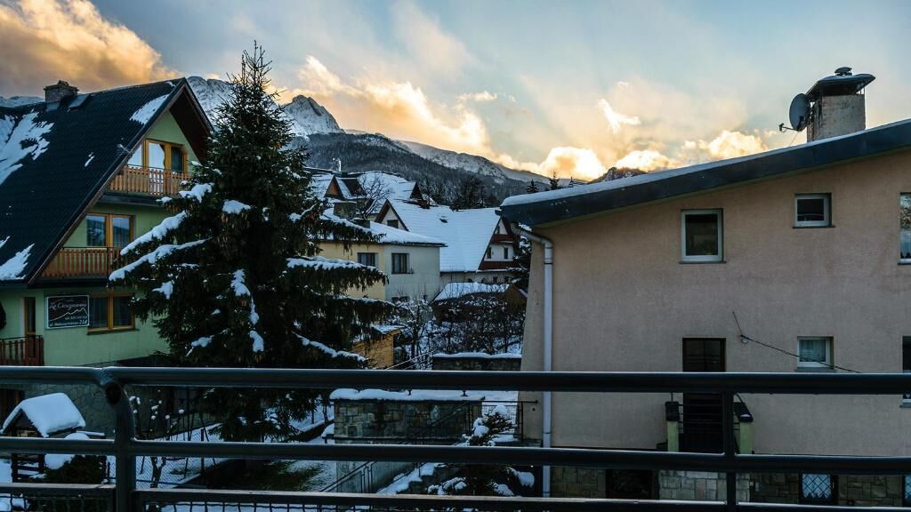 A residential area with snow-covered houses and mountains in the background.