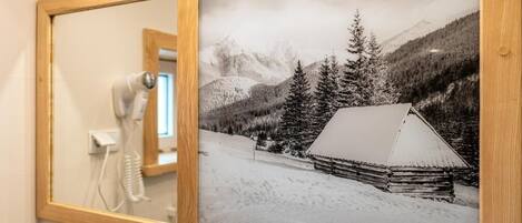 A framed black and white photograph of a cabin in a snowy landscape with mountains in the background.