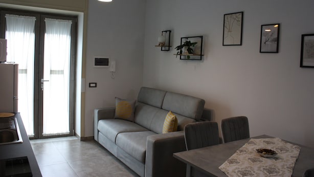 Una sala moderna con un sofá gris, una mesa de comedor con mantel estampado y obras de arte colgadas en la pared.