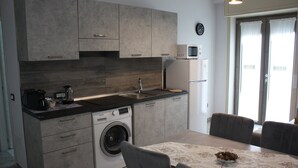 Una cocina moderna con armarios grises, lavadora integrada y un comedor con mesa para dos.