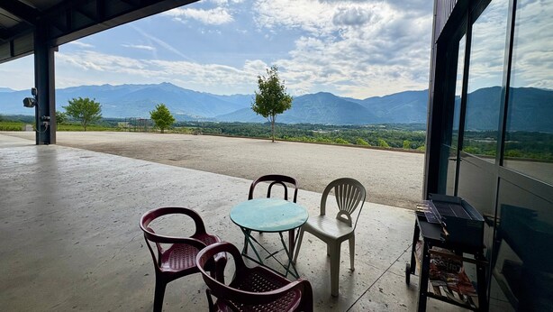 A covered outdoor seating area with a view of mountains and a clear sky.