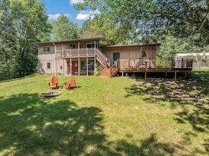 A two-story house with a front deck, a staircase leading to the upper level, and a small outdoor seating area with chairs. - Peaceful, Spacious, Dog Friendly, Workspace, Little Jay Gould | Eagle View Lodge (Cohasset)