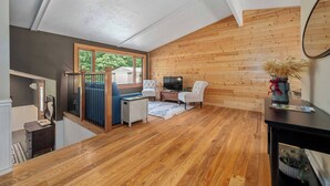 Un salon spacieux doté d’un plancher en bois, d’une grande fenêtre, d’un téléviseur et d’une cheminée.
