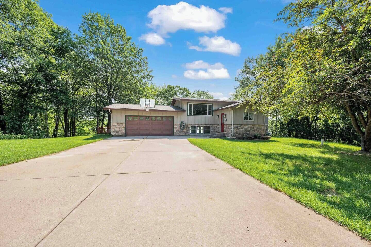 A single-story house with a garage, surrounded by trees and a well-maintained lawn.