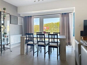 Un espace repas moderne comprenant une table et des chaises, un téléviseur et une vue sur l’extérieur.