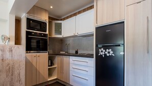 Una cuina moderna amb electrodomèstics d'acer inoxidable, armaris blancs i un frigorífic negre amb adhesius florals.