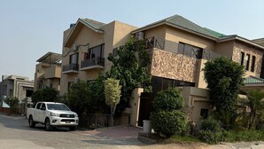 A multi-story residential building with balconies, a white pickup truck parked in front, and surrounding greenery. - Sundas Lodge (Islamabad)