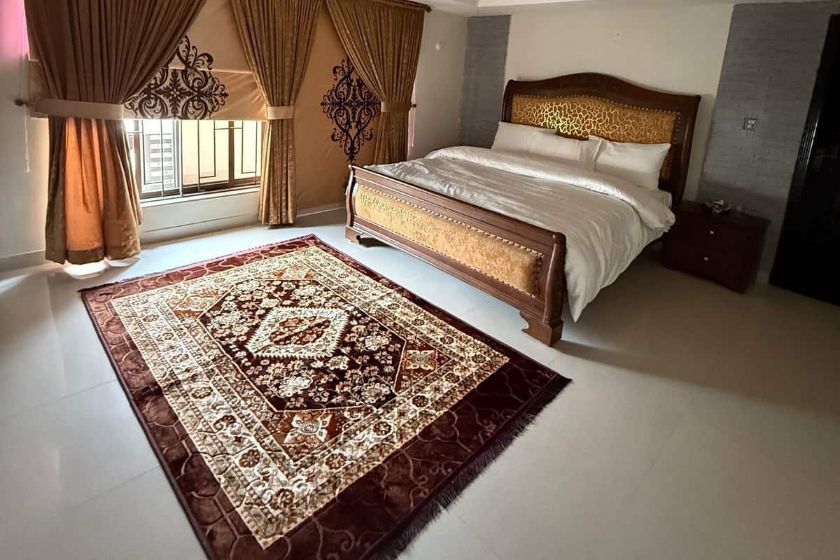 A spacious bedroom with a large bed, a ceiling fan, and a patterned rug.