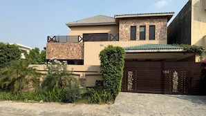 A two-story house with a stone facade, a tiled roof, and a gated entrance. - Sundas Lodge (Islamabad)