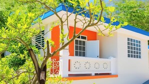 Un bâtiment à la façade blanche, agrémenté de touches de couleur orange et surmonté d’un toit bleu.