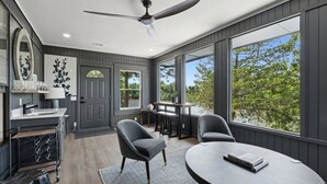 Una cocina moderna con horno empotrado, un comedor con mesa redonda y ventanas grandes que ofrecen vistas a árboles.