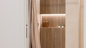 A bathroom with a wooden panel wall, a shelf with toiletries, and a small plant.