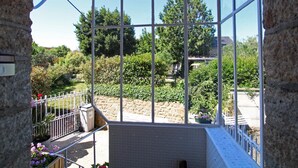 Une véranda dotée d’un toit en verre, de murs en pierre et offrant une vue sur un jardin.