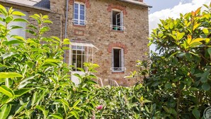 Un bâtiment en pierre doté de nombreuses fenêtres et d’un porche abrité.