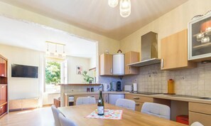 A modern kitchen with wooden cabinets, a stainless steel range hood, and a dining area with a table set for two.