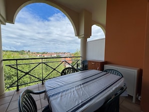 Un balcón con cama, sillas y vistas a un pueblo.