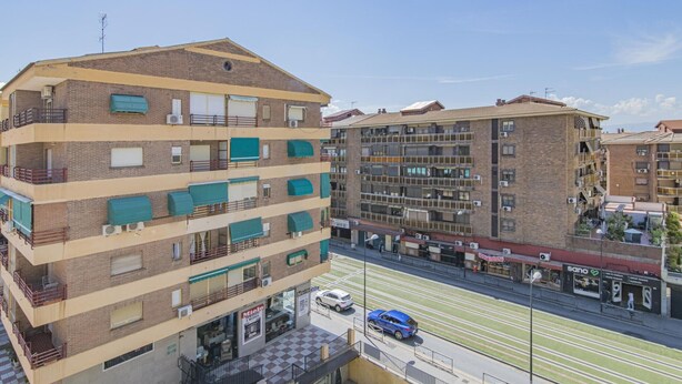 Un edificio residenziale a più piani con balconi, affaccio sulla strada e cielo sereno.