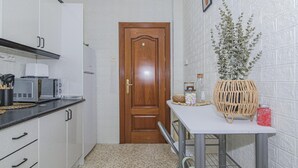 Una cucina compatta con mobili bianchi, un forno a microonde, un tostapane e una porta in legno.