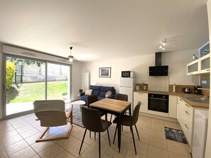 A modern apartment with a dining area, kitchen, and a living room with a sofa and a TV.