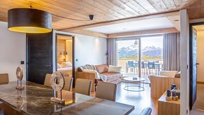 A modern hotel room with a wooden ceiling, a marble dining table, a sofa, and a balcony with a mountain view. - Luxury apartment spa & parking, Les Saisies, 11 people (Les Saisies)