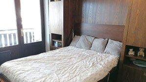 A bedroom with a bed, wooden headboard, and a small shelf with teddy bears. - Mountain Studio for 4 at Ski Slopes (Le Grand-Bornand)