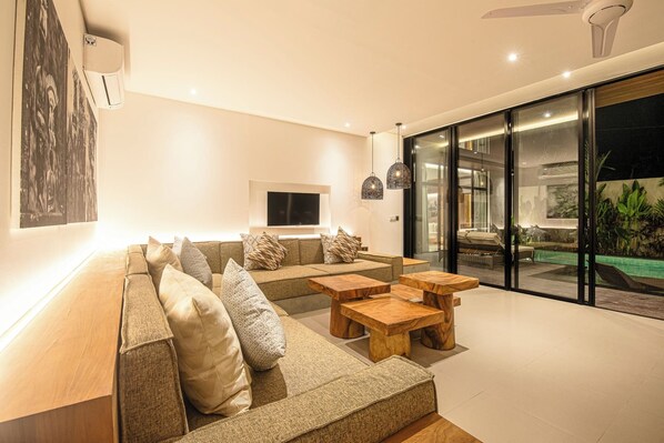 Een moderne woonkamer met een bank, houten bijzettafels en een televisie.