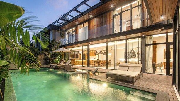 Une maison moderne dotée d’une piscine, d’un espace salon extérieur et d’une grande baie vitrée.