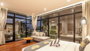Une chambre d’hôtel moderne, dotée d’un grand lit, d’un canapé et d’une table à manger. La chambre dispose de grandes fenêtres en verre et de rideaux.
