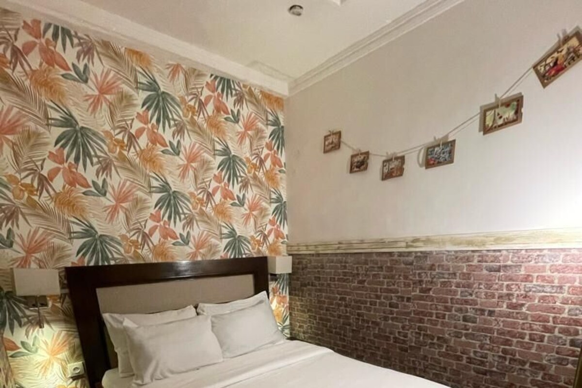 A bed with white bedding, a brick-patterned wall, and a striped rug.