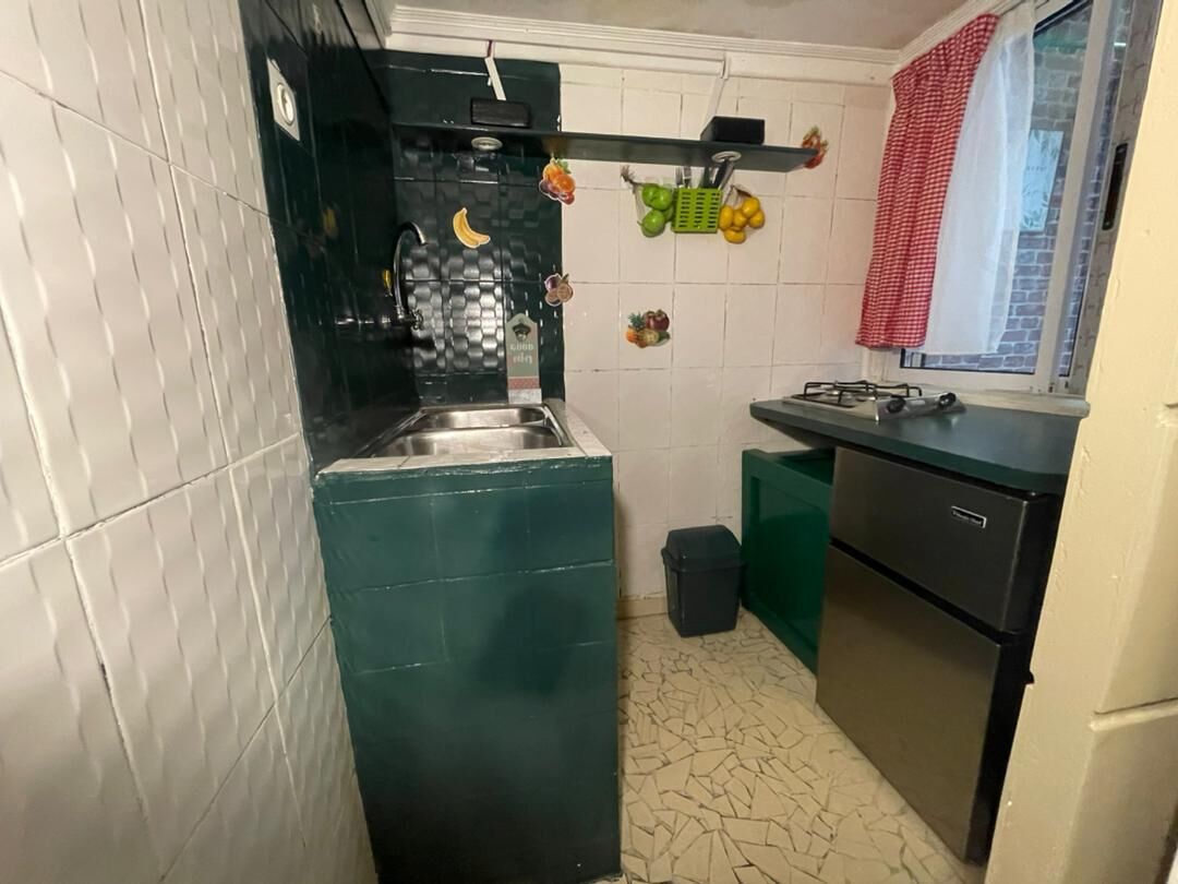 Une cuisine de taille réduite, équipée d’un évier, d’une cuisinière et d’une petite poubelle.