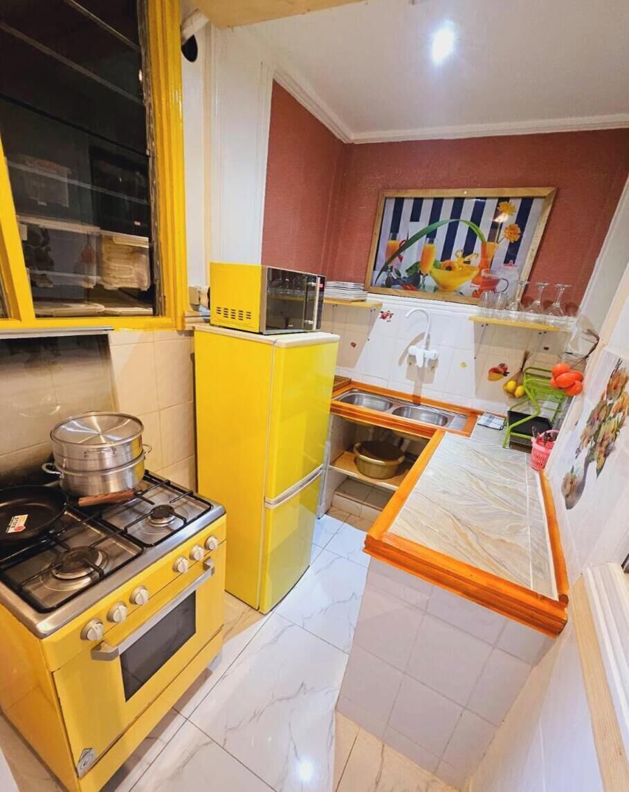 A compact kitchen with a yellow stove, a small refrigerator, and a sink.