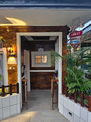 A hallway with a wooden wall, a welcome sign, a sign for a chalet, and potted plants.