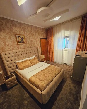 Een slaapkamer met een groot bed, nachtkastje, lamp en een dressoir.