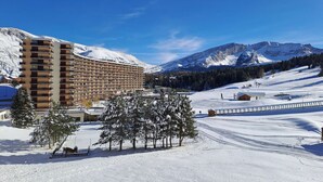 A hotel with a curved facade, multiple balconies, and a view of snow-covered mountains.