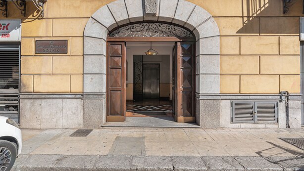 A building entrance with a stone archway, a wooden door, and a metal gate. - Kadì Apartment by Wonderful Italy (Palermo)
