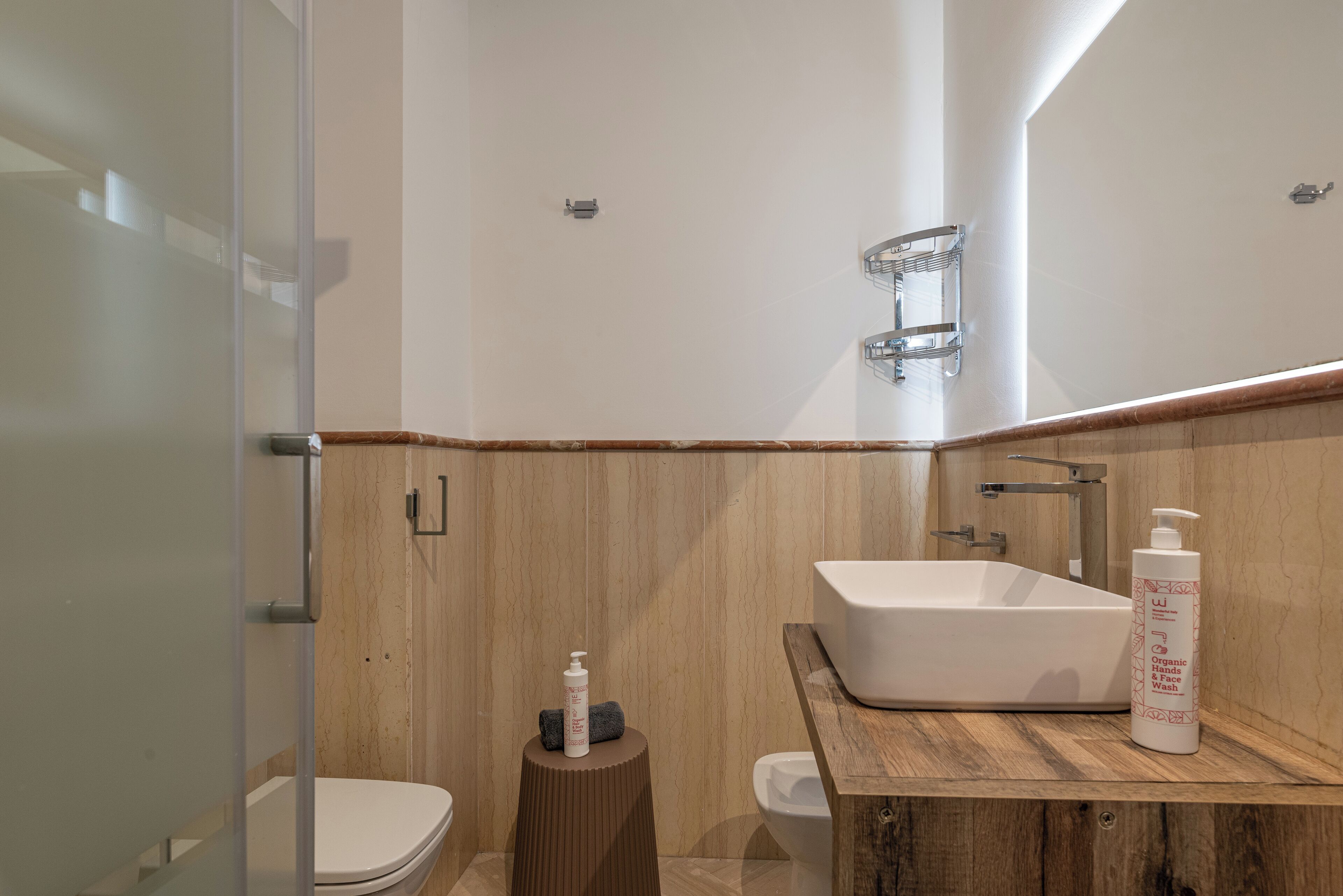 A modern bathroom with a glass shower enclosure, a wooden vanity with a large sink, and a toilet.