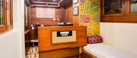 A compact room with a bed, a desk, and a patterned wall.