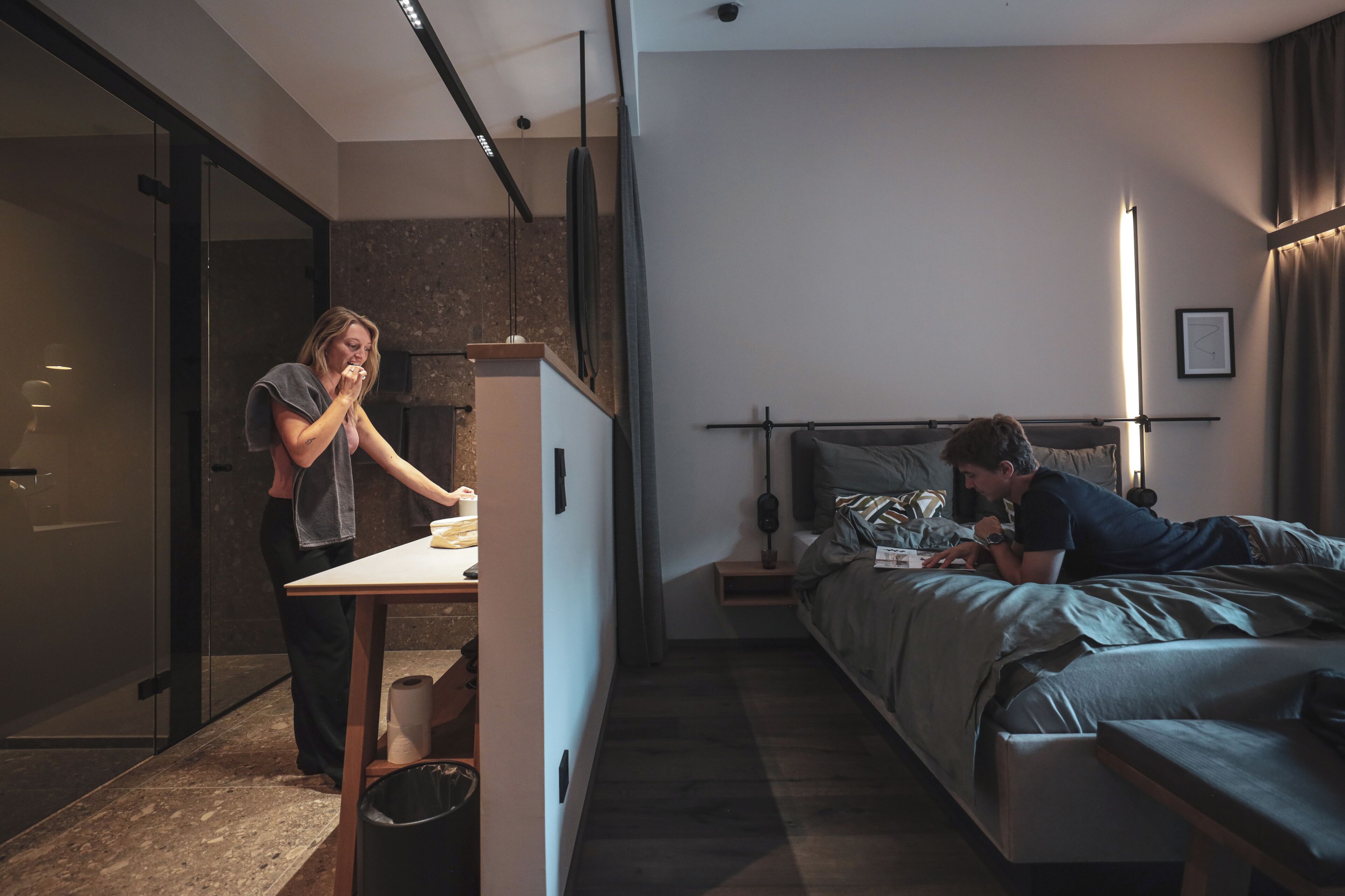 Ein modernes Hotelzimmer mit Bett, Nachttisch und einer kleinen Schreibtischzeile.