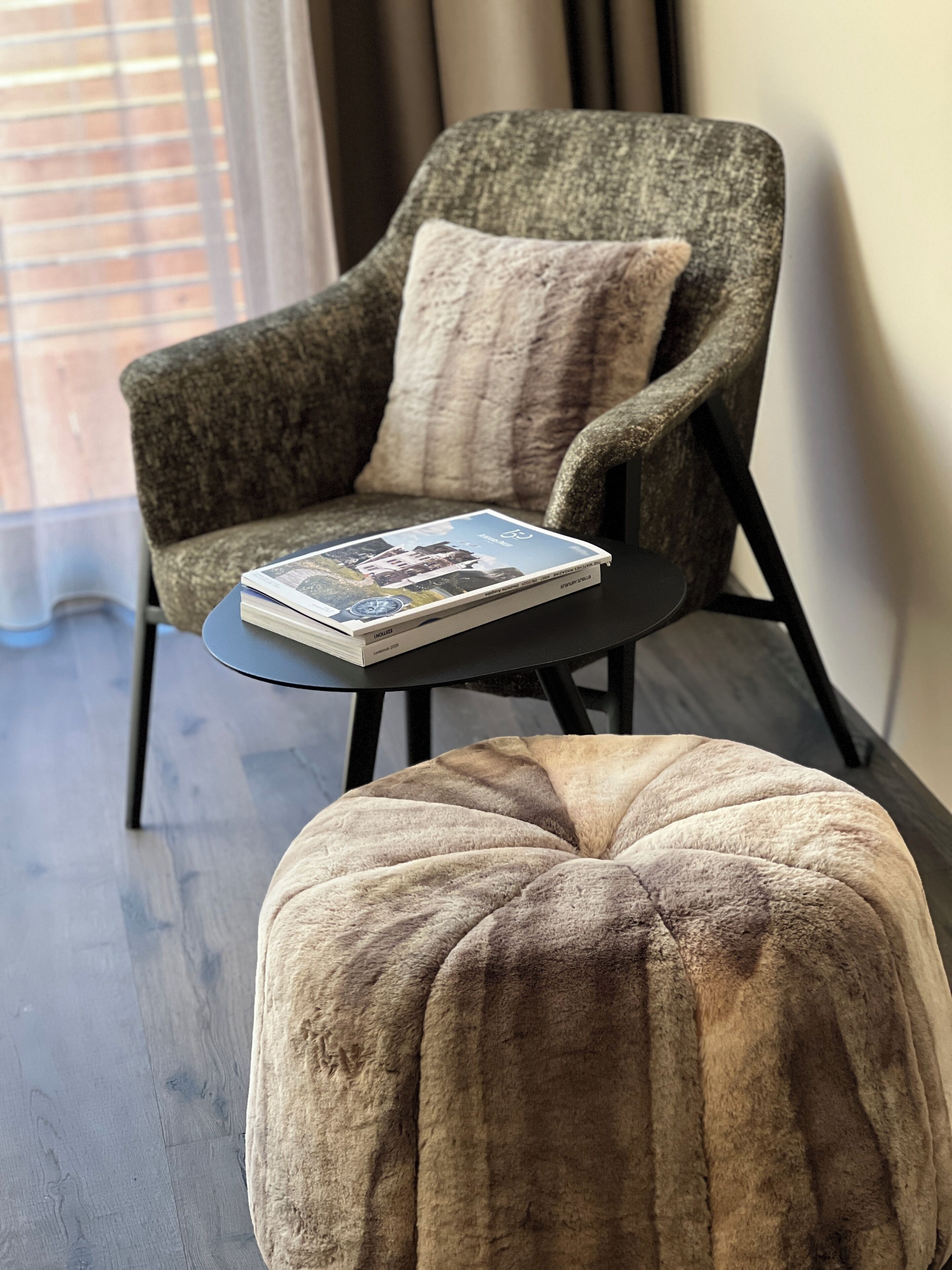 A chair with a cushion and a small table with a book.